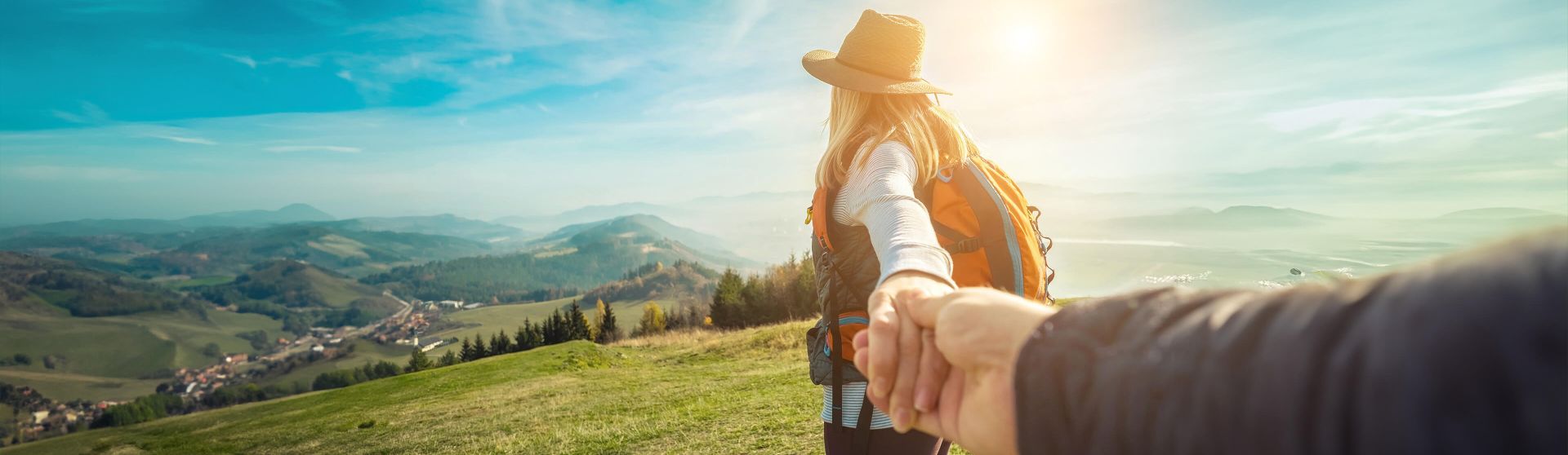 Frau blickt vom Berg ins Tal und hält die Hand ihres Mannes.