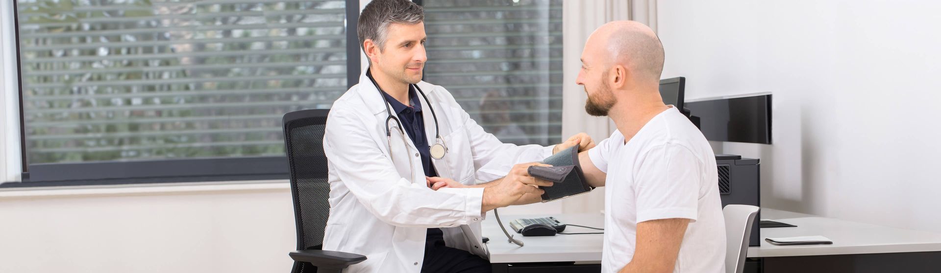 Arzt misst den Blutdruck eines Patienten.