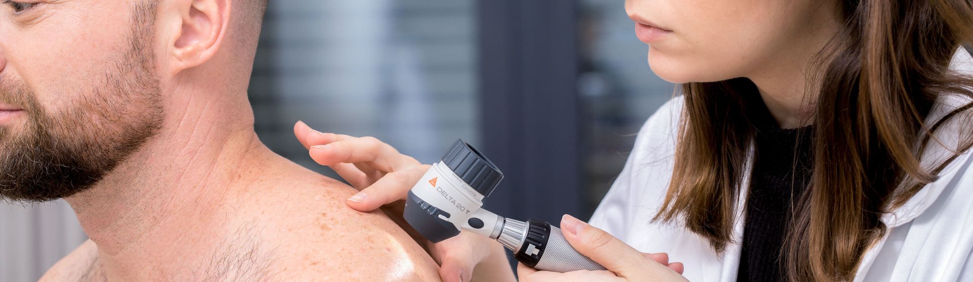 Dermatologin untersucht mit einem Dermatoskop die Haut eines Patienten.