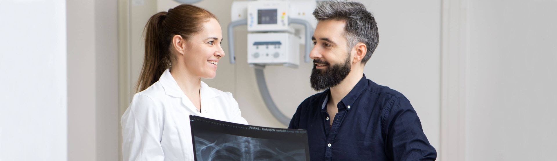 Radiologin erklärt einem Patienten eine Röntgenaufnahme.